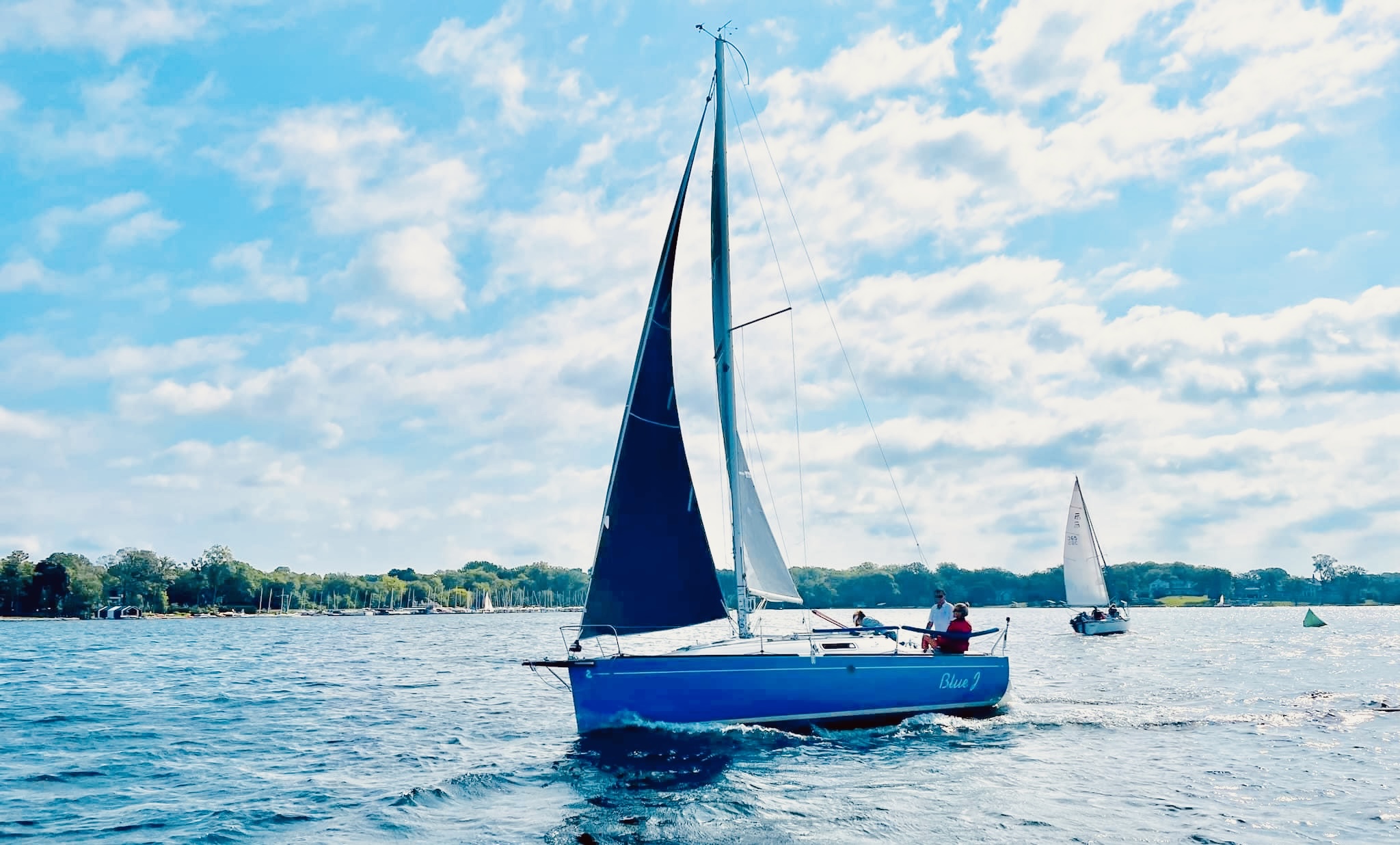 Day sailing on Lake Minnetonka with crew and guests, blue hull sailboat